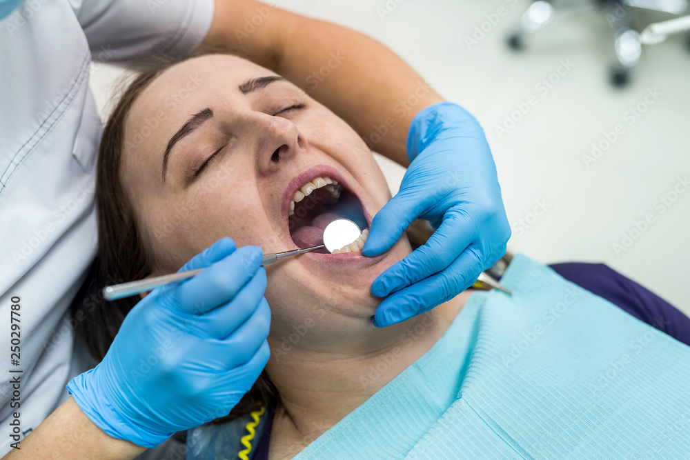 Doctor in dentistry examining patient's teeth with mirror Doctor in dentistry examining patient's teeth with mirror