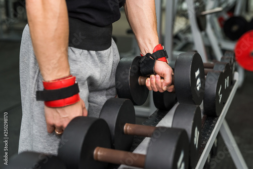 Male hands with dumbbells in gym close up