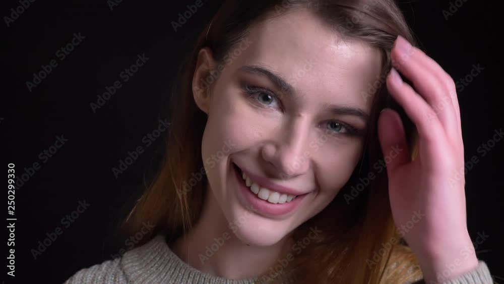 Closeup portrait of young cute feminine caucasian girl smiling cheerfully and fixing her hair posing in front of the camera Closeup portrait of young cute feminine caucasian girl smiling cheerfully and fixing her hair posing in front of the camera
