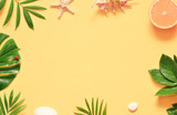 Tropical background. Palm trees branches with starfish and seashell on yellow background. Travel.