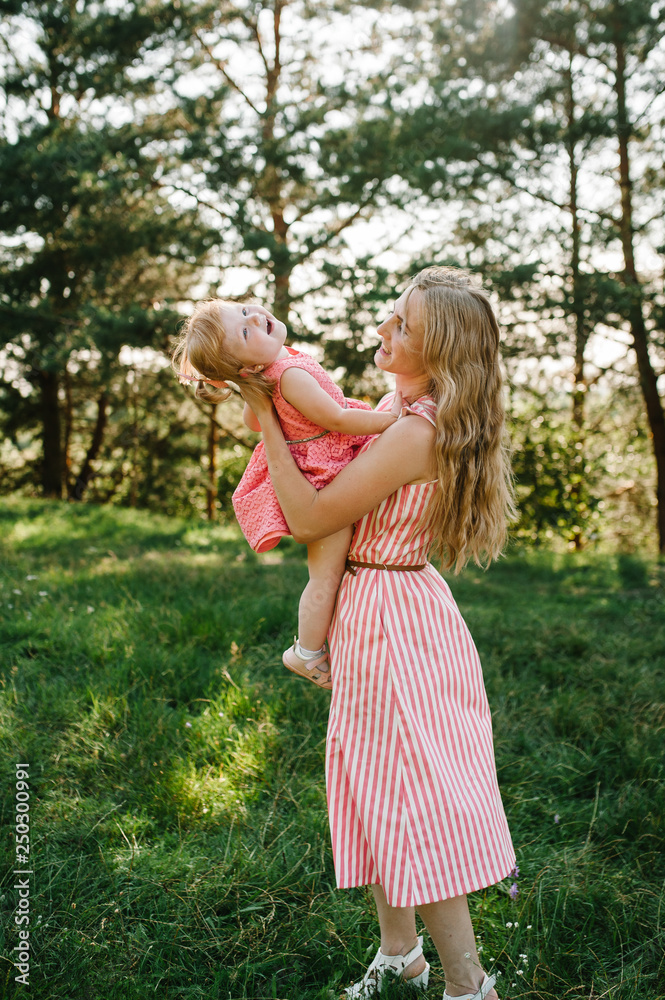 Portrait of a mother holds, throws up and spins the daughter on hands on nature on summer day vacation. Mom and girl playing in the park at the sunset time. Concept of friendly family. Close Up. Portrait of a mother holds, throws up and spins the daughter on hands on nature on summer day vacation. Mom and girl playing in the park at the sunset time. Concept of friendly family. Close Up.