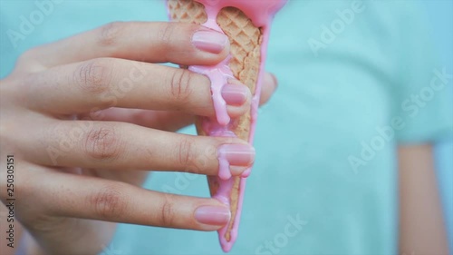 young afro girl eating pink melting ice cream at blue wall background