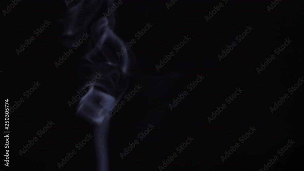 Slow motion shot of incense smoke rising against black background. Slow motion shot of incense smoke rising against black background.