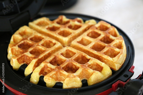 Belgian waffles in electric waffle iron. Cooking healthy breakfast, freshly baked classic wafer