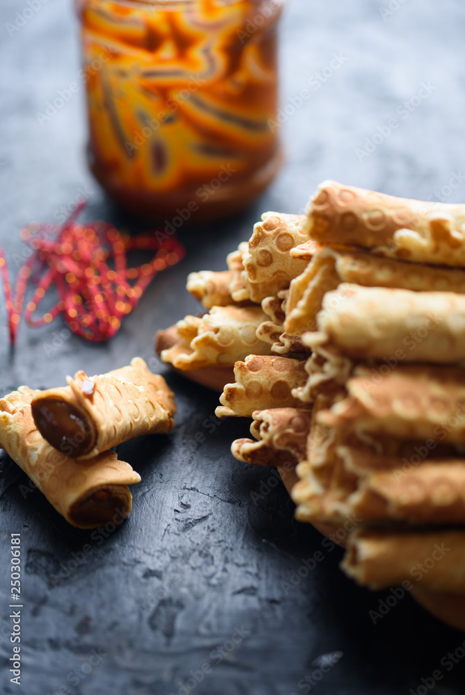 Wafer rolls, tasty and fragrant, with boiled condensed milk on a black table Wafer rolls, tasty and fragrant, with boiled condensed milk on a black table