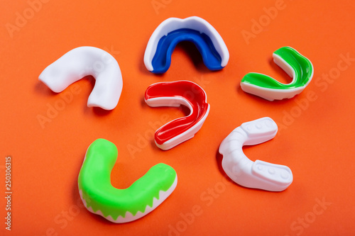 Lots of boxing protective mouthguards on orange background, concept photo