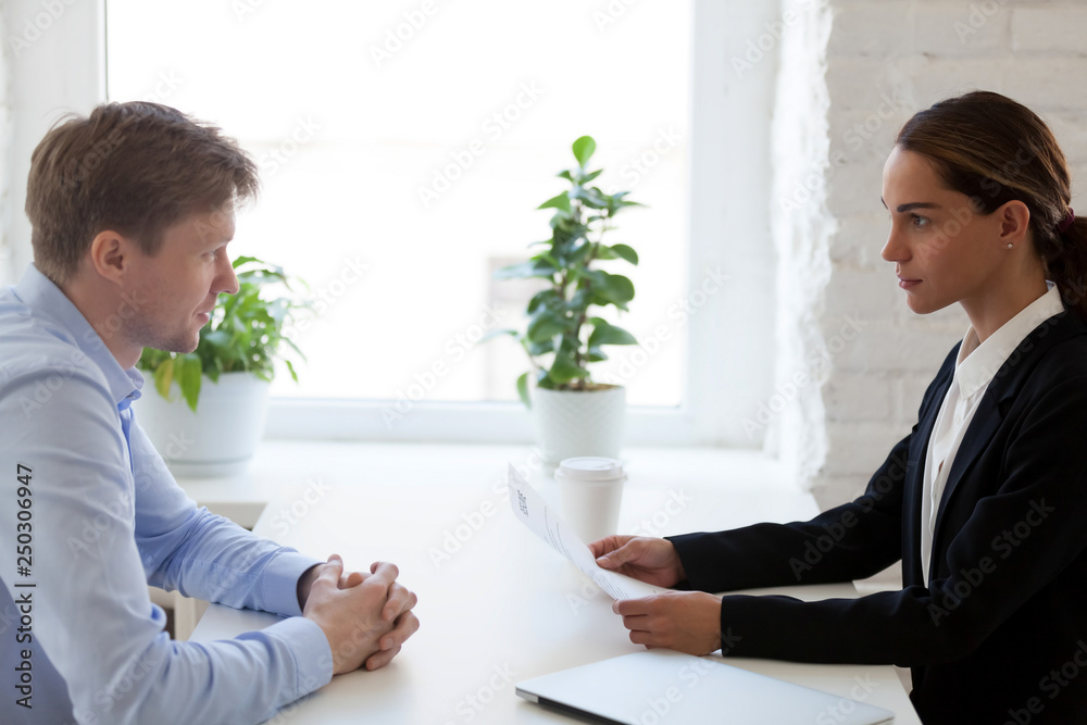 Job candidate and HR manager sitting at desk at interview Job candidate and HR manager sitting at desk at interview