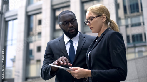 Colleagues consider project on tablet, marketers choose place for advertising