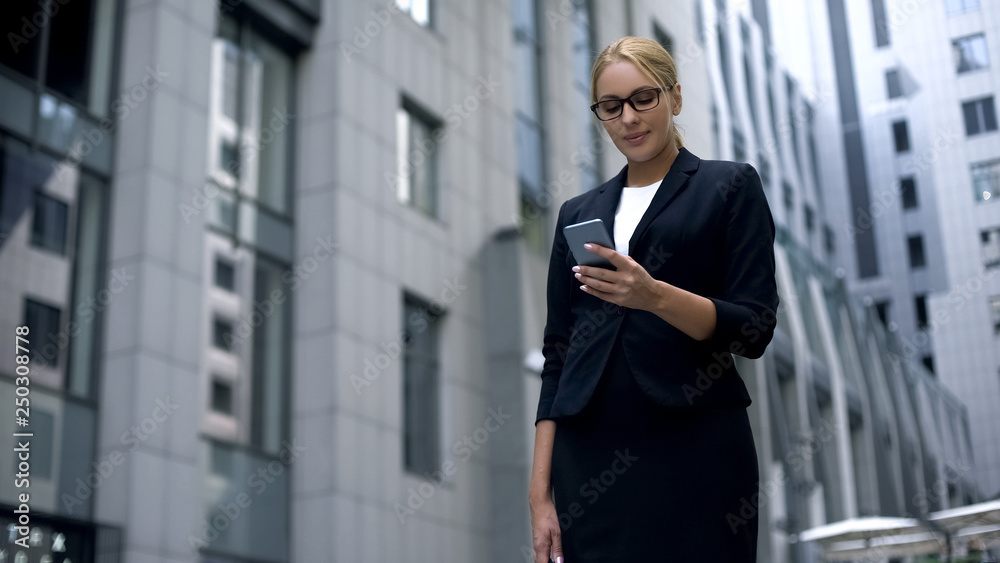 Smiling businesswoman happy to read message on smartphone with good news, salary