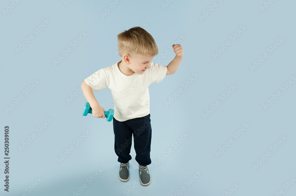 sporty little boy with dumbbells shows his muscles on an isolated blue background. The concept of a healthy lifestyle sporty little boy with dumbbells shows his muscles on an isolated blue background. The concept of a healthy lifestyle