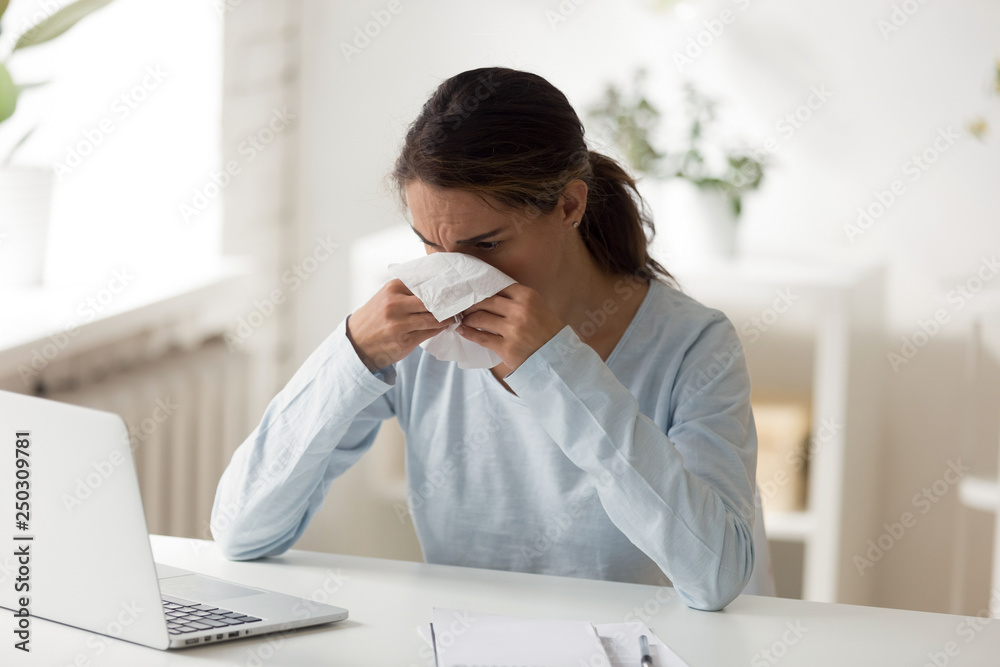 Unhealthy female sitting at workplace blowing nose Unhealthy female sitting at workplace blowing nose