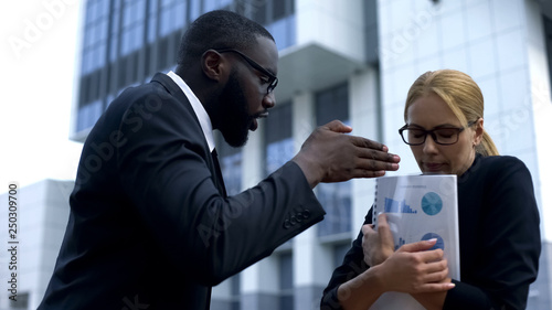 Aggressive boss shouting at female employee, criticizing for mistake in report