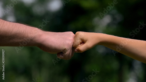Man and child punching fists, parents as reliable support for children, closeup © motortion