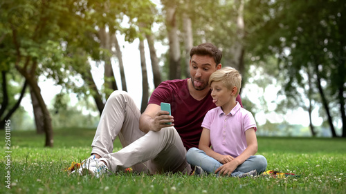 Father and child taking selfie with smartphone, capturing happy family moment © motortion