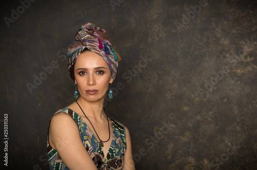 A beautiful slender dark-haired girl in a turban and ethnic clothes indoors with an Eastern interior. photo