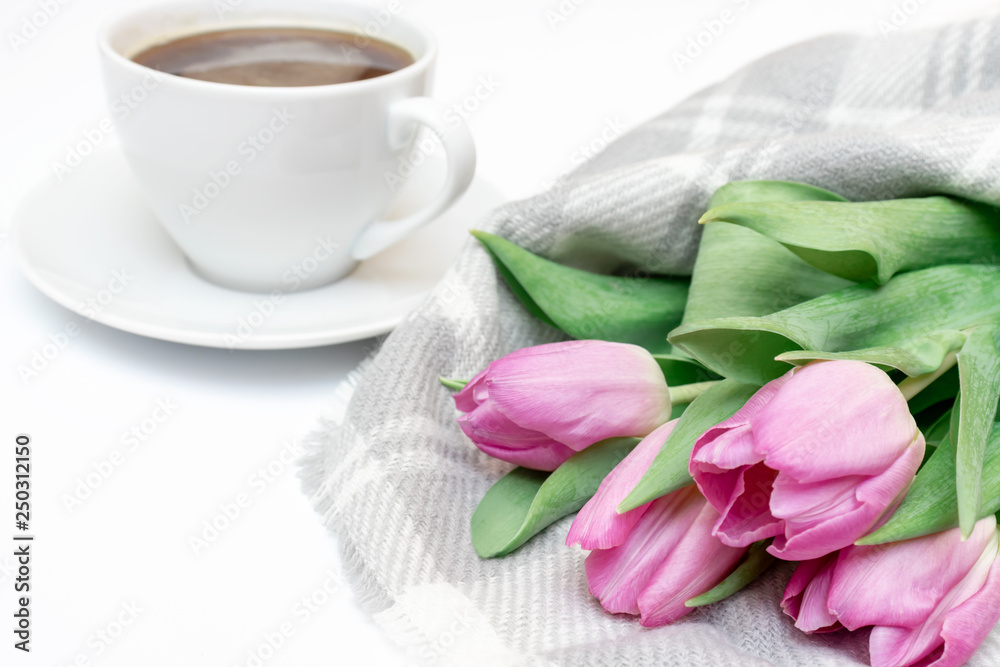 Woman working desk with coffee mug, notebook and spring pink bouquet of tulip flowers, feminine flat lay style