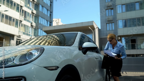 Workaholic woman gets out of car, throwing papers, bad day at work absent-minded photo