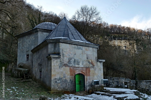 View toward temple with tomb, foundation of ancient building and stone door toward cliff in Demir Baba Teke, cult monument honored by both Christians and Muslims in winter near Sveshtari village photo