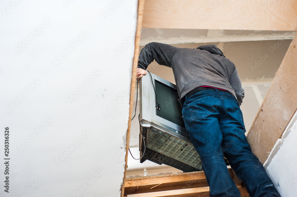 Fototapeta premium Worker brings the TV up the stairs
