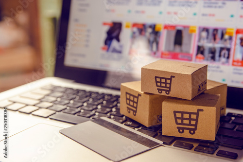 Shopping online. Cardboard box with a shopping cart logo in a trolley on a laptop keyboard payment by credit card and offers home delivery. photo