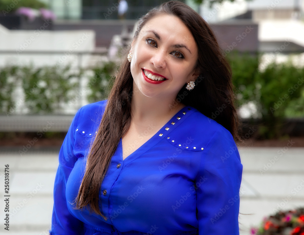 young beautiful Hispanic business women with blue shirt outside of the office building smiling during head shots