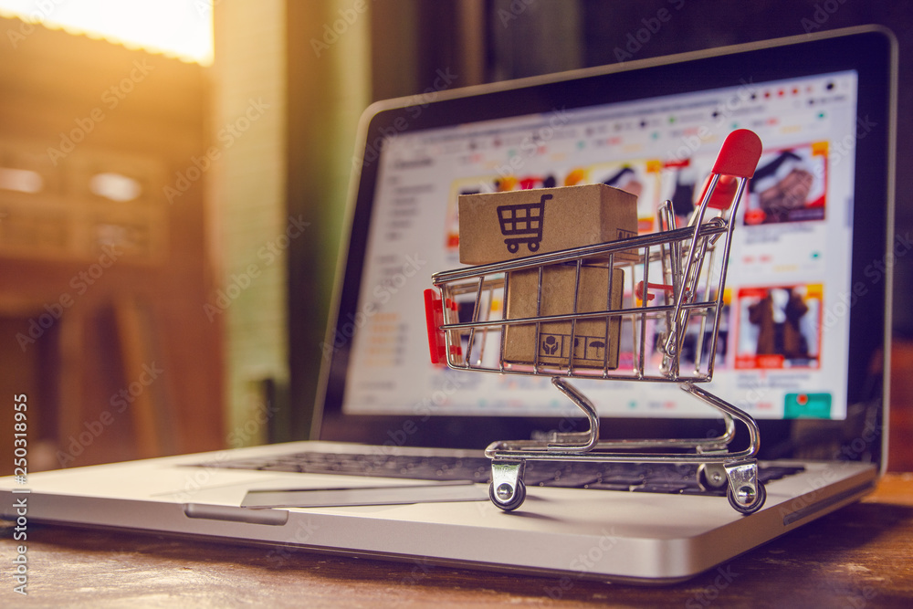 Shopping online concept - Parcel or Paper cartons with a shopping cart logo in a trolley on a laptop keyboard. Shopping service on The online web. offers home delivery.