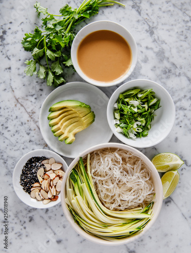 Ingredients for asian rice noodle dish with avocado, parsley, vegetables, almonds and sesame seeds