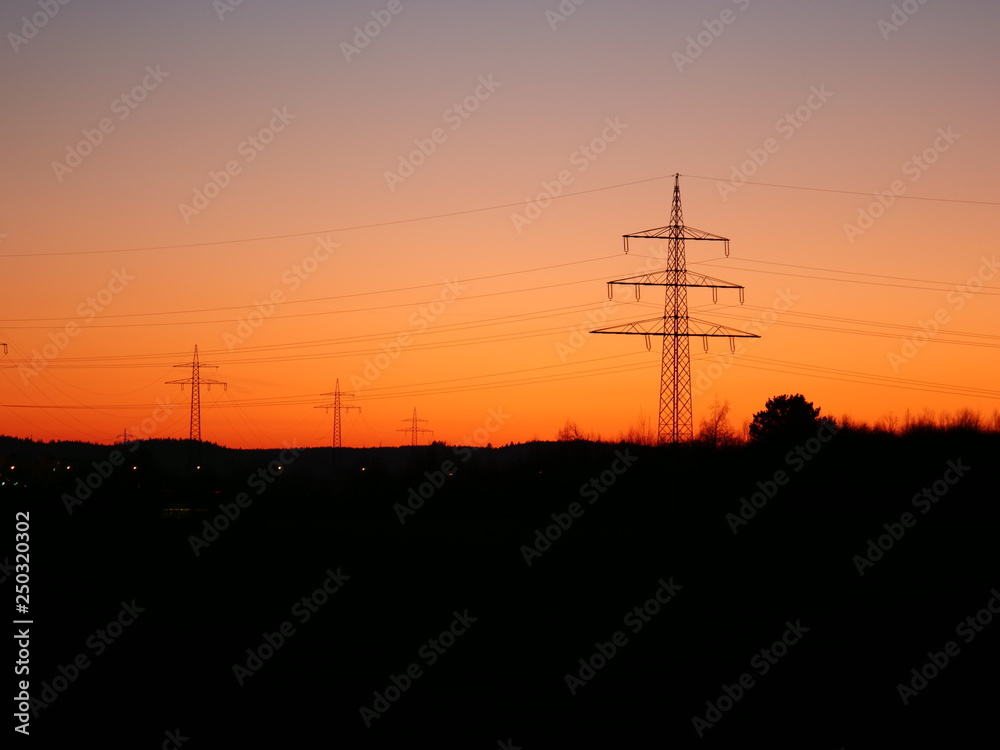 Image of power pylons in the landscape during colorful sunset