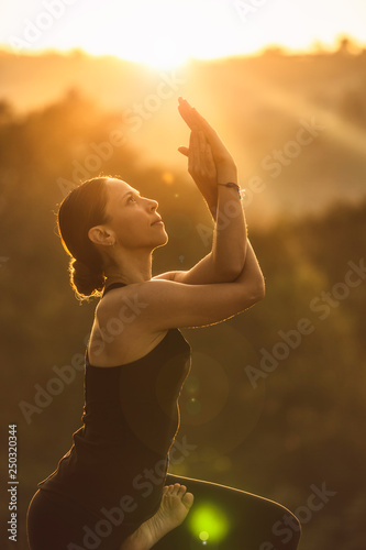 Portrait of mindful female practicing yoga in eagle posture. With the nature during sunrise in the morning. Peaceful, mindfulness and Healthcare concept. Soft focus and soft light.