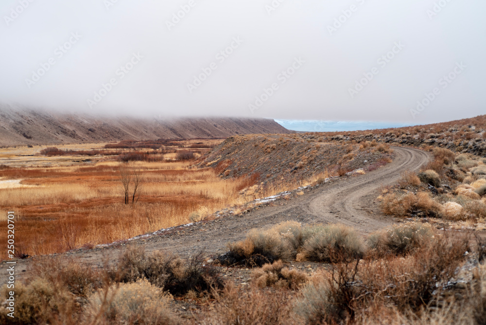 dirt roads in valley landscape with heavy cloudy mist layer obscuring the hills and mountains of the Sierra Nevada
