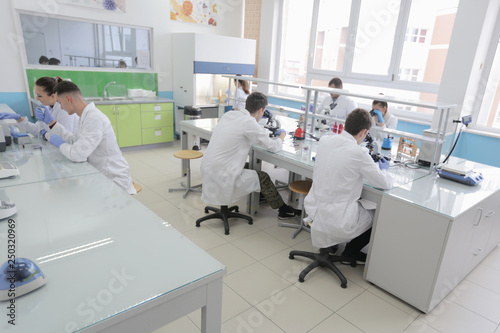Group of young Laboratory scientists working at lab with test tubes and microscope, test or research in clinical laboratory.Science, chemistry, biology, medicine and people concept.