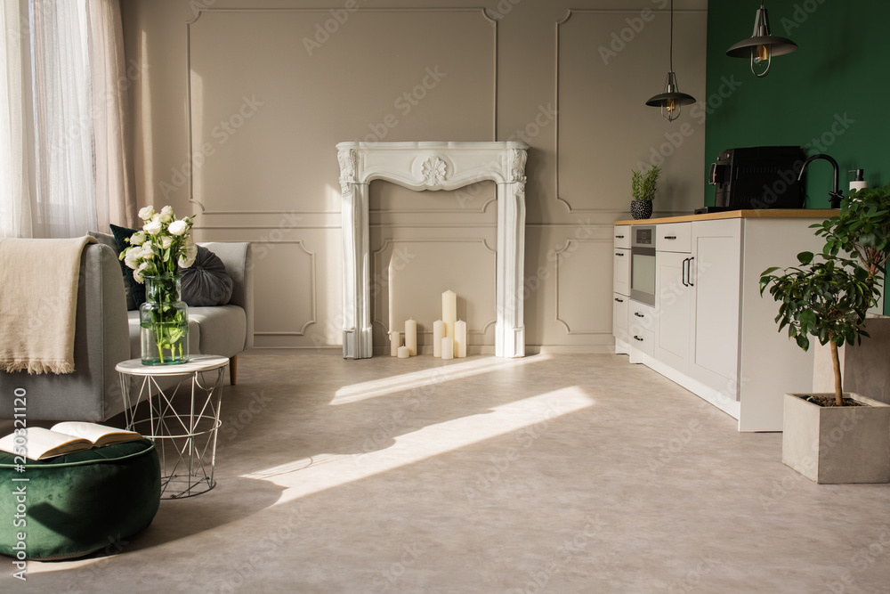 Fototapeta premium Open plan kitchen and living room with plants and grey fireplace portal with candles