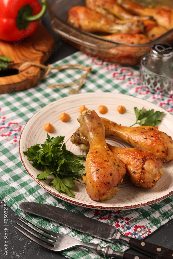 Chicken drumsticks baked in mustard marinade located on a plate against a dark background