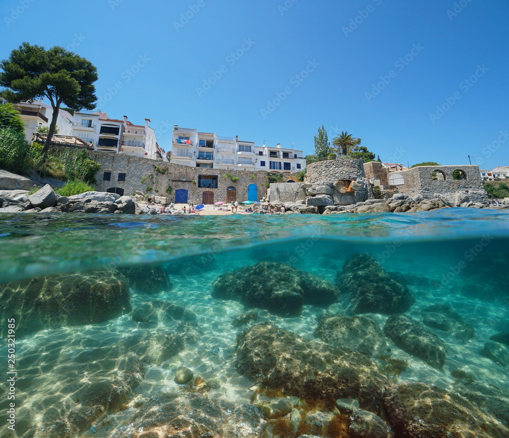 Spain Calella de Palafrugell coastline, small beach and rocks underwater, Costa Brava, Mediterranean sea, Catalonia, split view half over and under water