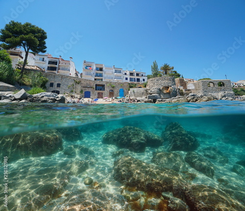 Spain Calella de Palafrugell coastline, small beach and rocks underwater, Costa Brava, Mediterranean sea, Catalonia, split view half over and under water