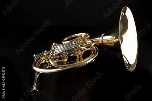 French horn on a wooden table. Beautiful polished musical instrument. photo