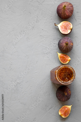 Top view, fig jam in glass jar and fresh figs on concrete background. Flat lay, from above, overhead. Copy space.