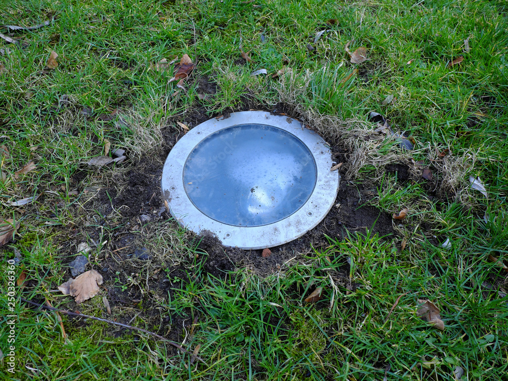Ground light in the park switched off during the day. Located in the grass. Ground light in the park switched off during the day. Located in the grass.
