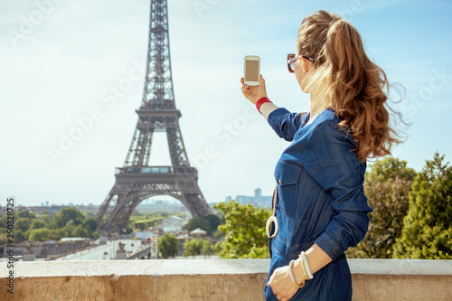 woman against Eiffel tower taking photo with smartphone © Alliance
