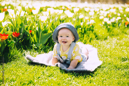 Baby in green grass of tulip field at springtime photo