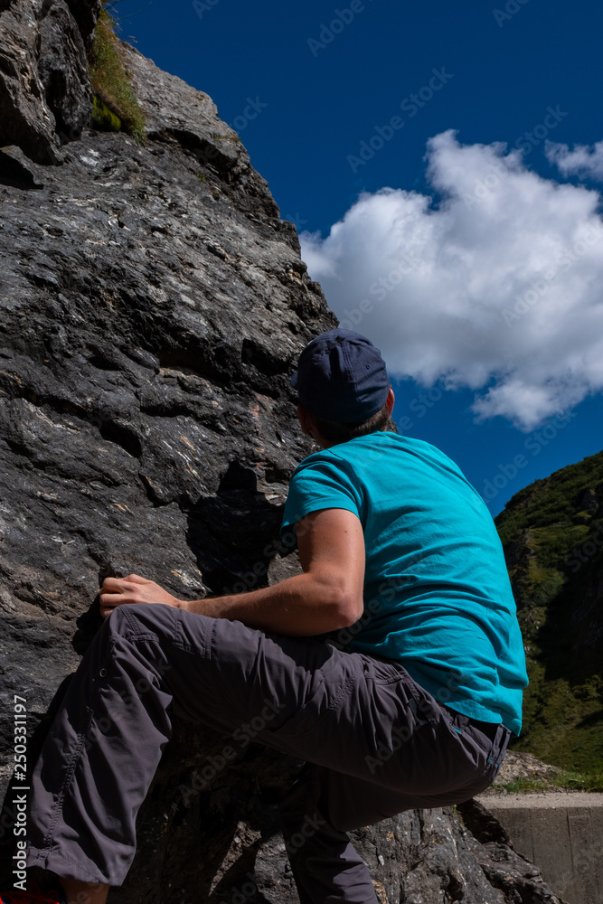 Fototapeta premium Young caucasian man is climbing on a rock in Switzerland