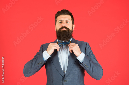 Man bearded hipster wear classic suit outfit. Formal outfit. Take good care of suit. Elegancy and male style. Businessman or host fashionable outfit on red background. Fashion concept. Classy style