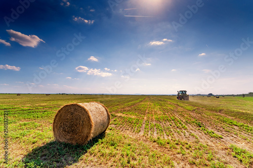 Hay bales and tractor in the field in countryside after harvest in summer