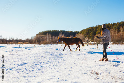 The girl in the winter field is engaged in training with her foal