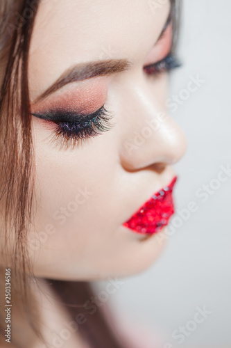 Stylish young brunette with bright and stylish makeup. Eye shadow with arrows and bright red lips