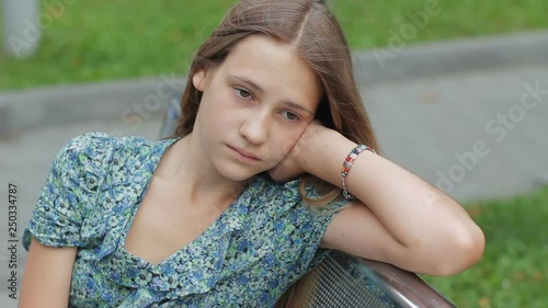 Sad depressed teenager girl sitting alone on the park bench