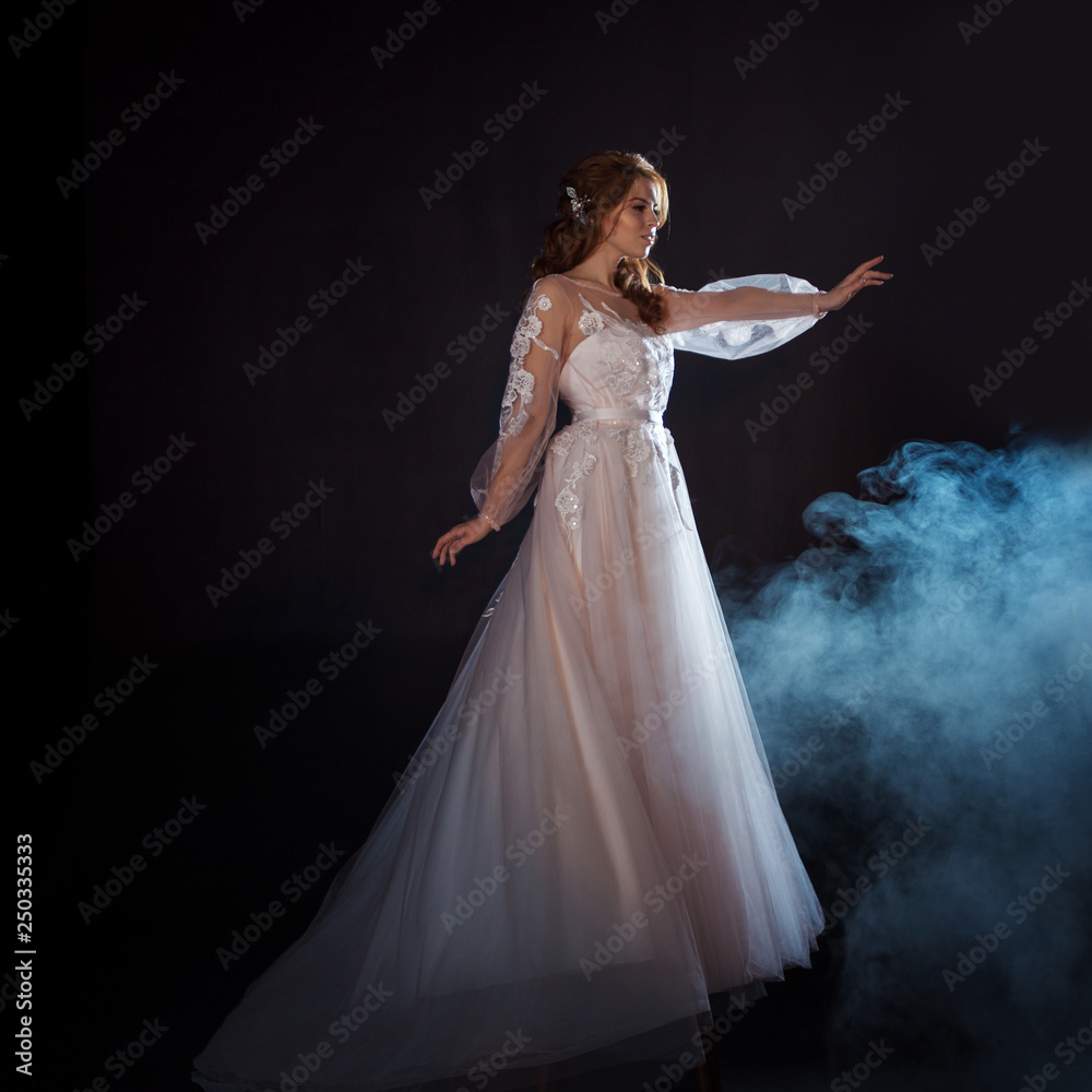 Young beautiful woman in wedding dress with wide light skirt. Dark background, fantasy style