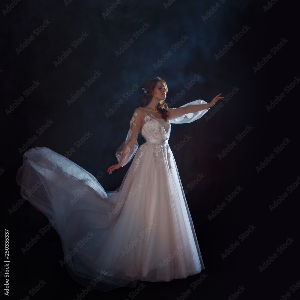 Young beautiful woman in wedding dress with wide light skirt. Dark background, fantasy style Young beautiful woman in wedding dress with wide light skirt. Dark background, fantasy style