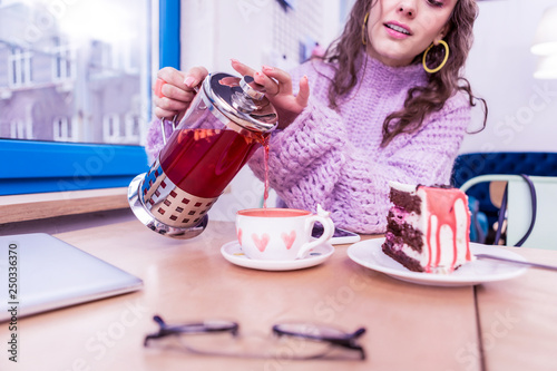 Attentive careful lady pouring hot tea in pretty cup photo