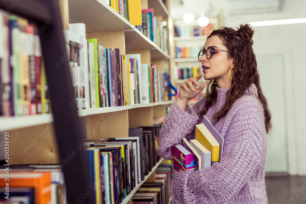 Thoughtful positive lady choosing between two books Thoughtful positive lady choosing between two books